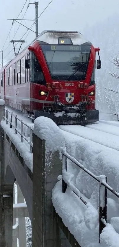 Red train crossing snowy mountains.