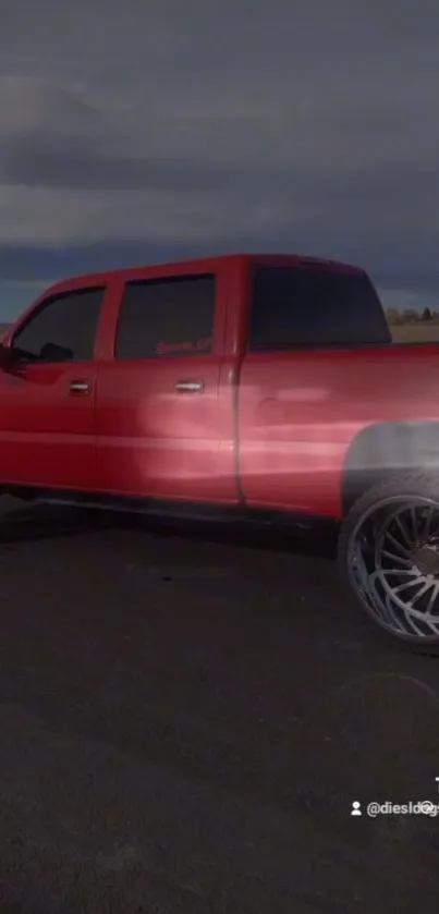 Red pickup truck on open road in sunlight.