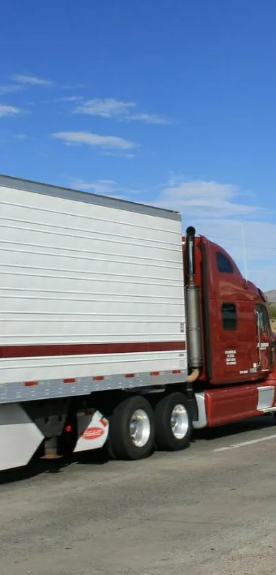 Red truck on an open highway under a bright blue sky.