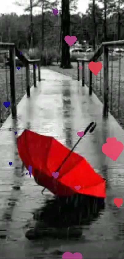 Red umbrella on a wet bridge with colorful hearts in black and white setting.