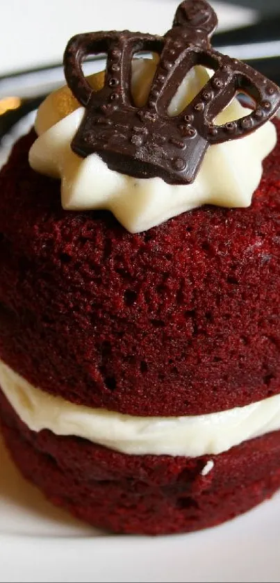 Red velvet cupcake with cream and chocolate crown on a white plate.