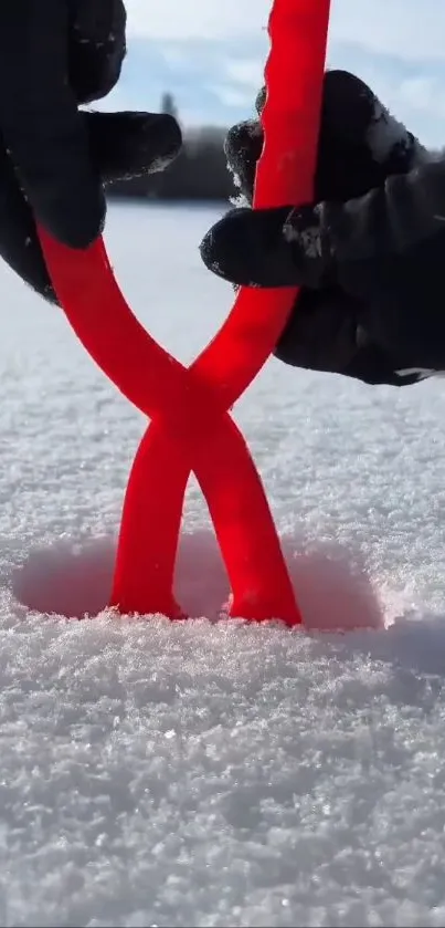 Hands holding red yarn in snowy landscape.