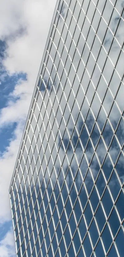 Glass building reflecting sky with clouds.