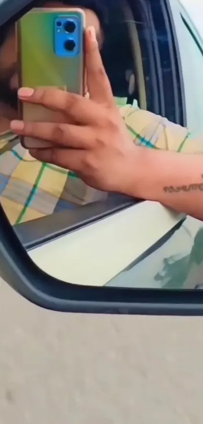 A hand holding a phone in a car mirror reflection.