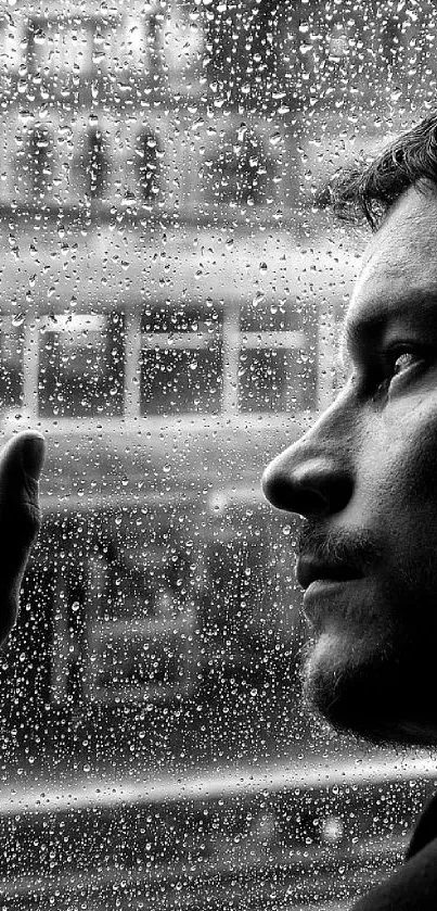 Pensive man looks through a rainy window in black and white.