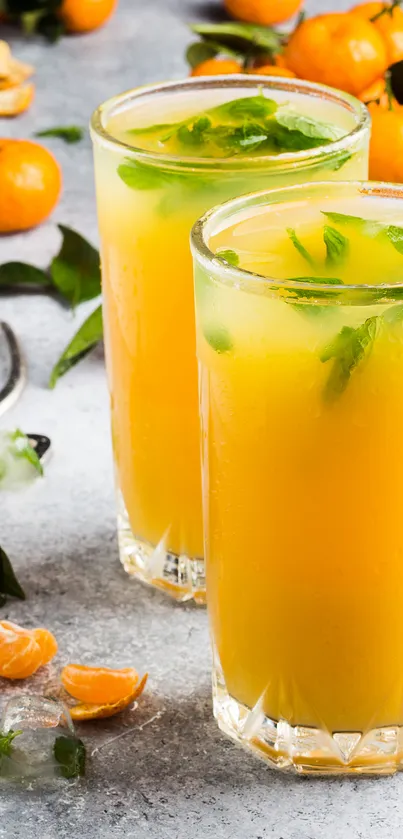 Two glasses of citrus drink with orange and mint garnish.