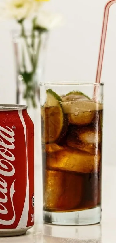 Glass of iced cola with can beside it and flowers in the background.