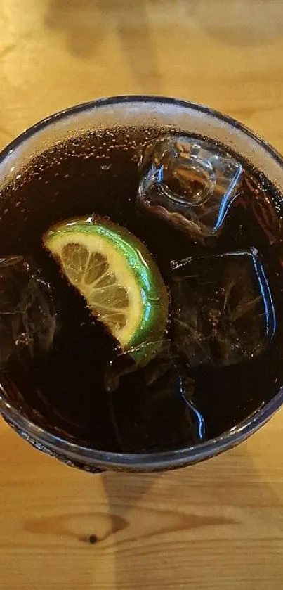 Top-down view of cola with lime slice, on a wooden table.