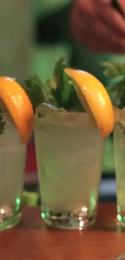 Lemon cocktail with ice and green leaves on a wooden bar.