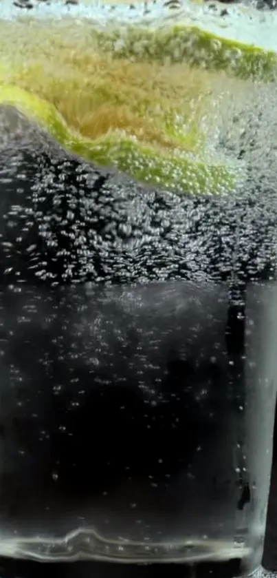 Glass of sparkling water with lime wedge on black background.