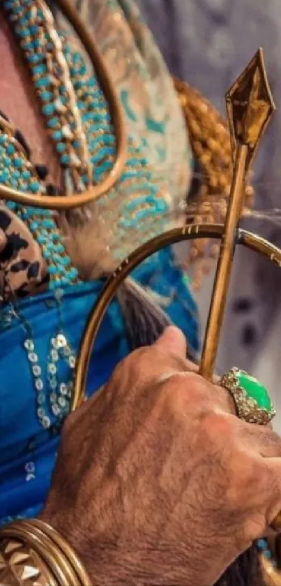 Close-up of a regal hand holding a golden scepter with a green gemstone ring.