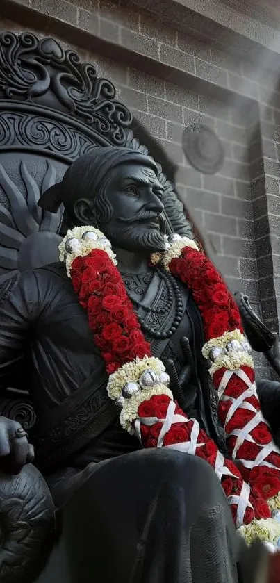 Regal statue adorned with a red and white garland on a mobile wallpaper.