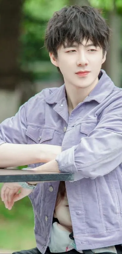 Person in lilac jacket relaxing outdoors with green trees.