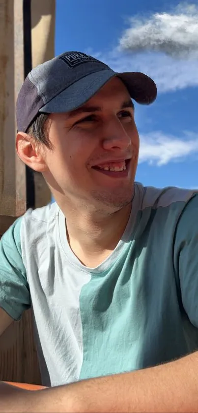 Man in a cap, smiling under clear blue sky.