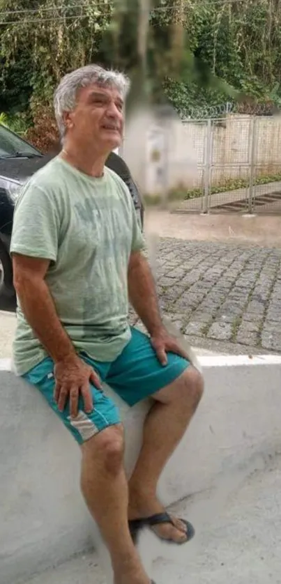 A man relaxing outdoors on a stone bench in casual attire.