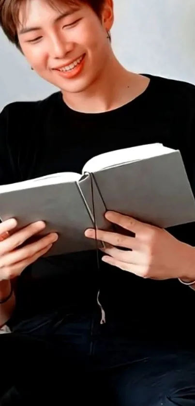 Person in black shirt reading a book with a relaxed expression.