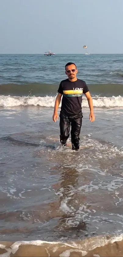 Man walking on a sunny beach with ocean waves.