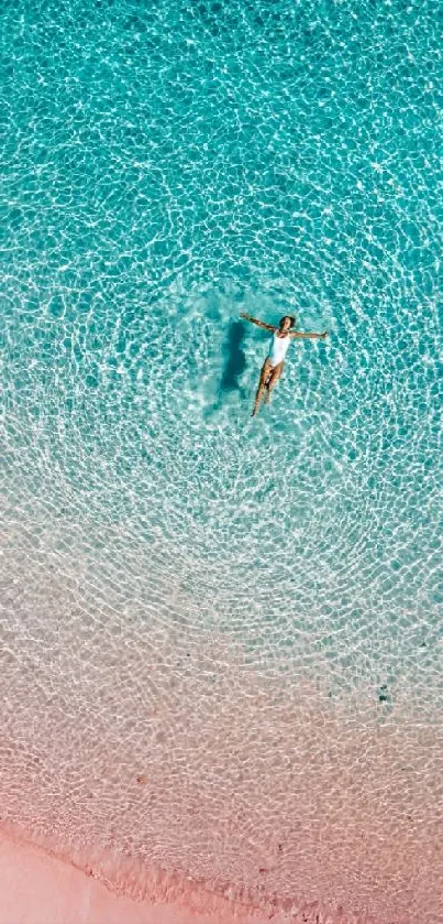 Aerial view of a person floating on turquoise water at a serene beach.