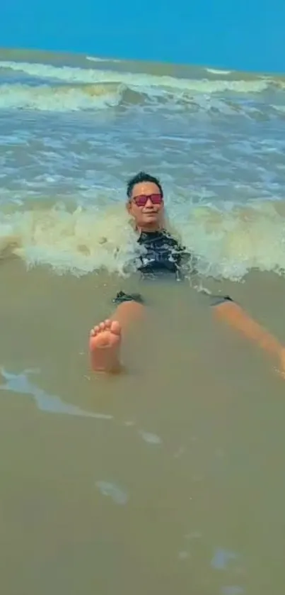 Man relaxing at the beach in ocean waves under a clear blue sky.