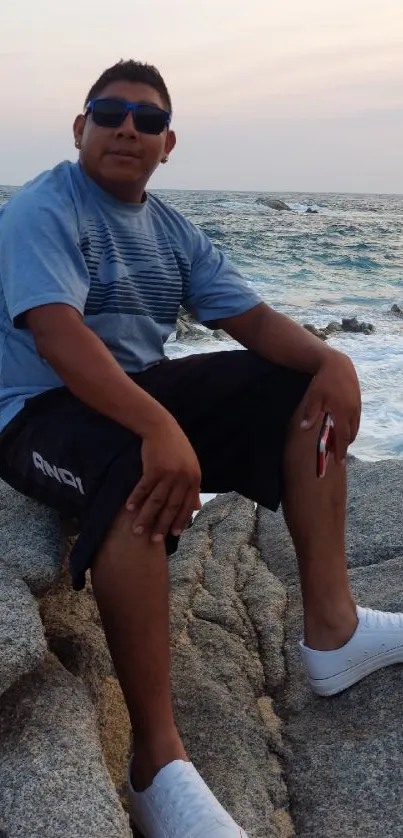 Person relaxing on rocks by the oceanfront under a calm sky.