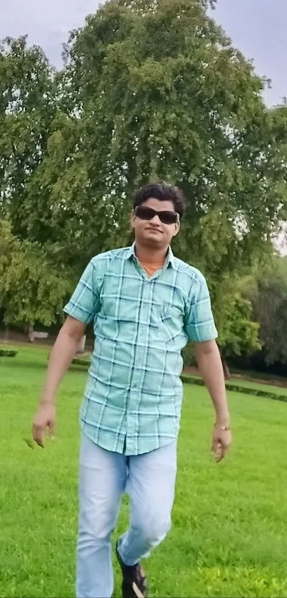 Man in sunglasses walking in a green park.