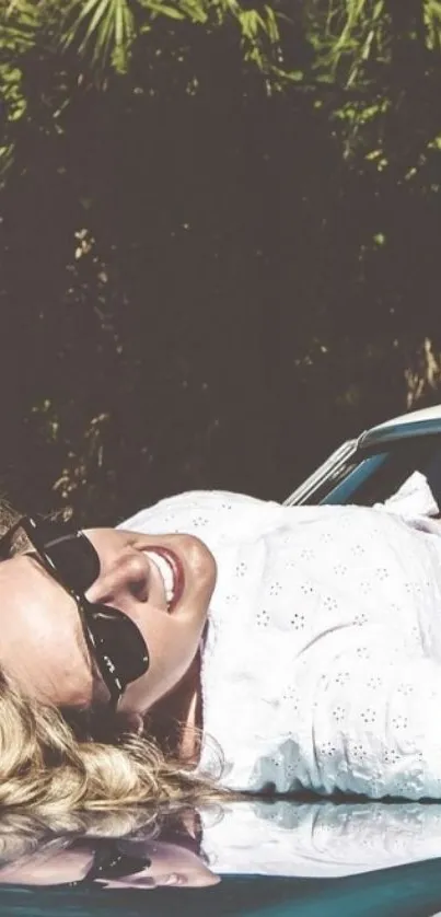 Woman in sunglasses relaxing on car in summer.