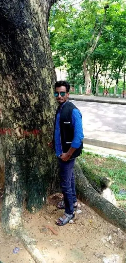 Person leaning against a large tree in a park setting.