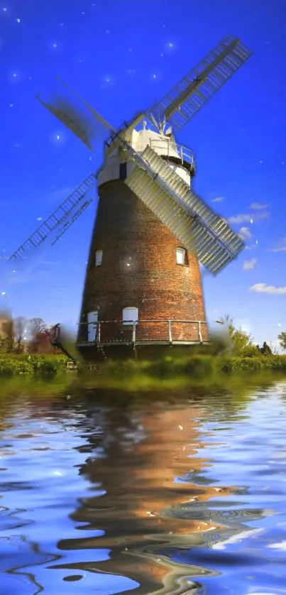 Picture of a windmill reflecting in calm water with a blue sky backdrop.