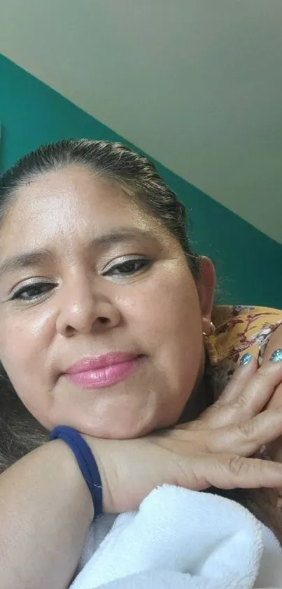 Woman resting indoors with teal background and colorful nails.