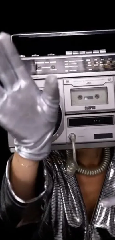 Person with a boombox head wearing silver metallic gloves.