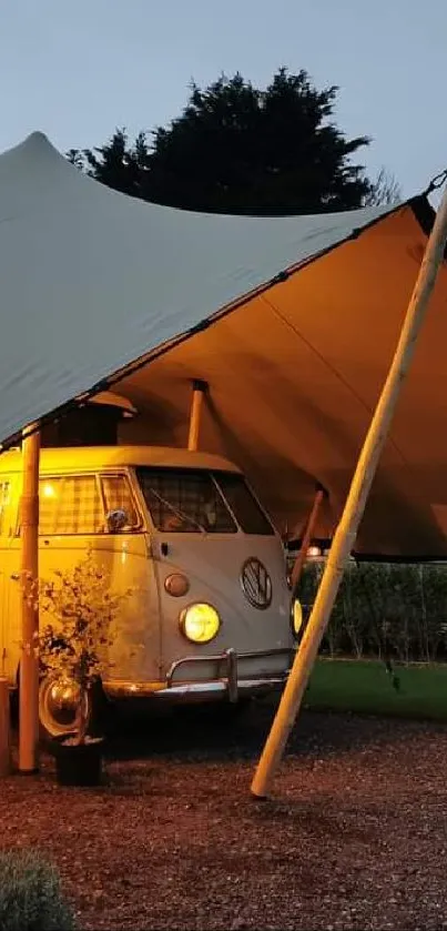 Retro camper van under tent with warm evening light.