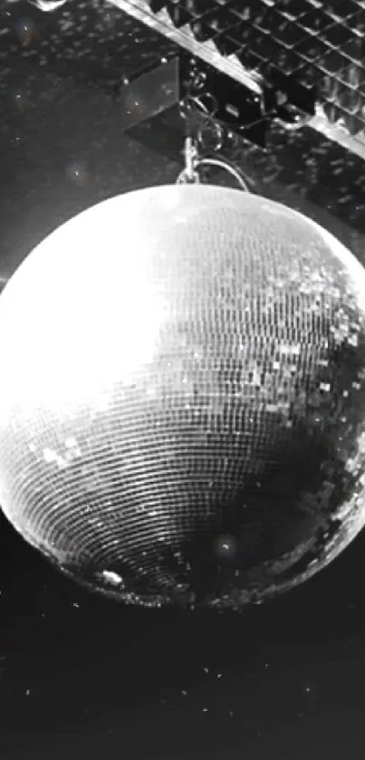 Shiny disco ball with reflective surface hanging in a dark room.