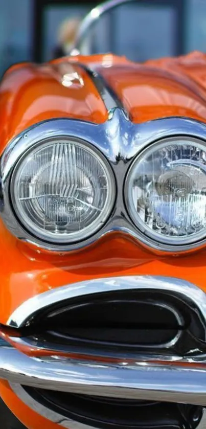 Vintage orange car with chrome headlights and stylish design.