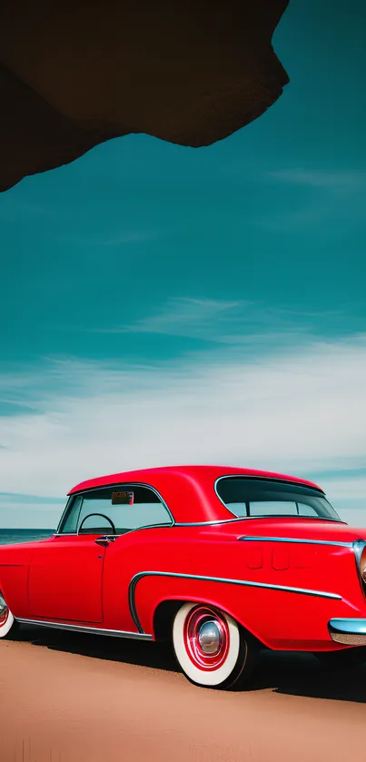 Vibrant red retro car on a tranquil beach under a teal sky.