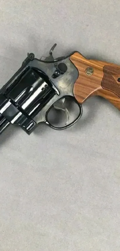 Classic revolver with wooden grip on gray background.