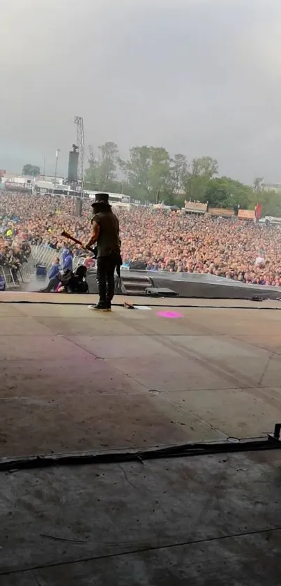 Musician performing on stage to a large outdoor audience.