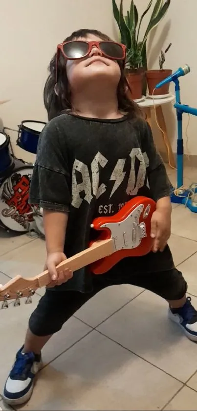 Kid in sunglasses playing toy guitar joyfully.