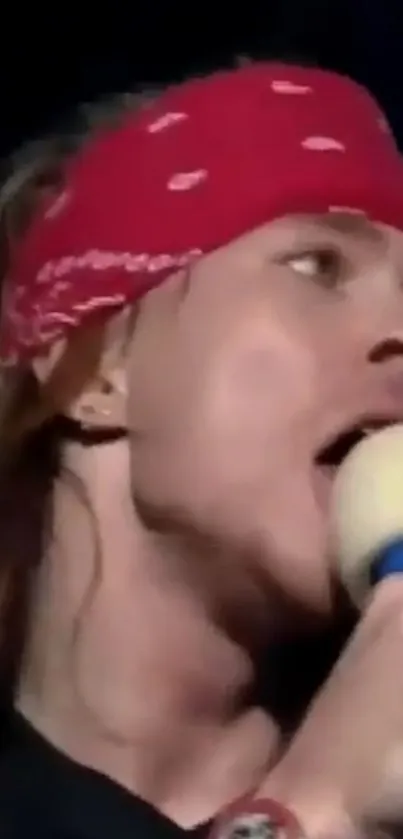 Rockstar singing with red bandana and microphone close-up.