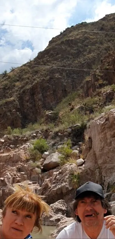 People explore rocky canyon landscape under cloudy sky.