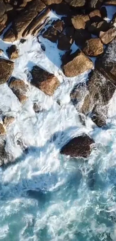 Aerial view of ocean waves crashing against rocks on a serene coastline.