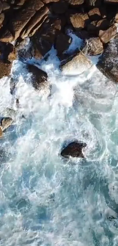 Aerial view of waves crashing on rocky shore with blue and white foamy sea.