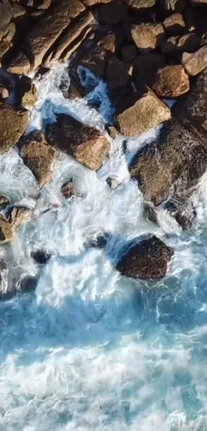 Aerial view of rocky shoreline and ocean waves in blue and white hues.
