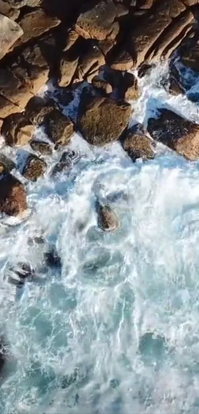 Aerial view of rocky shores with white waves crashing against them.