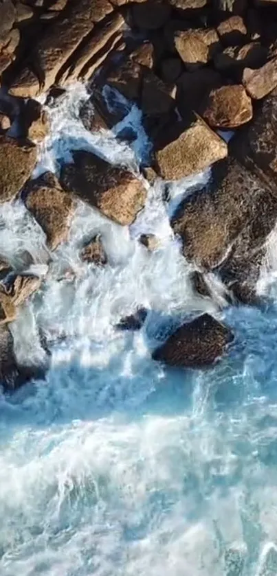 Aerial view of waves crashing on a rocky shoreline, captured in a mobile wallpaper.