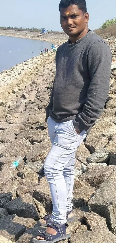 Person standing on rocky shore by water.