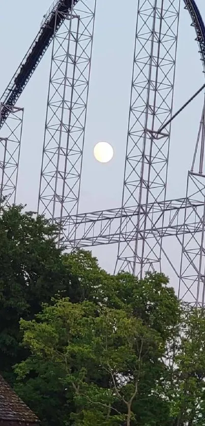 Roller coaster under moonlit sky with trees and scenic view.