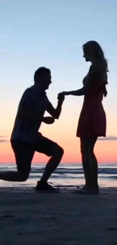 Silhouette of a couple in a romantic beach proposal at sunset.