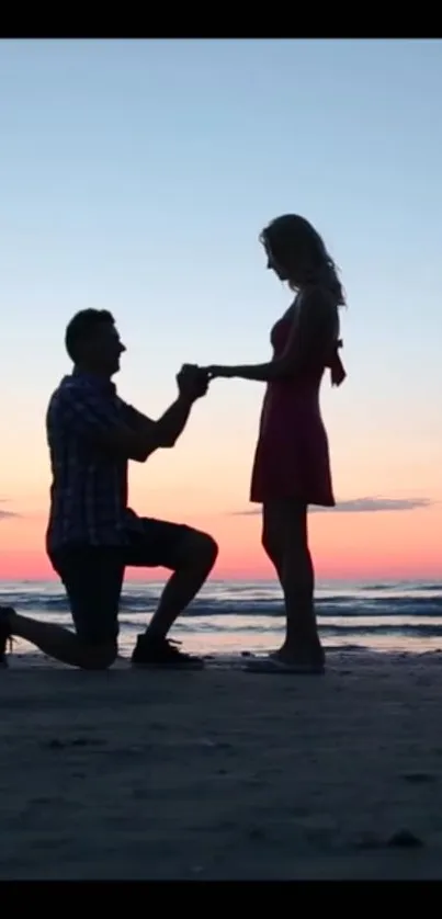 Silhouette of a couple's proposal on a beach at sunset with vivid sky colors.