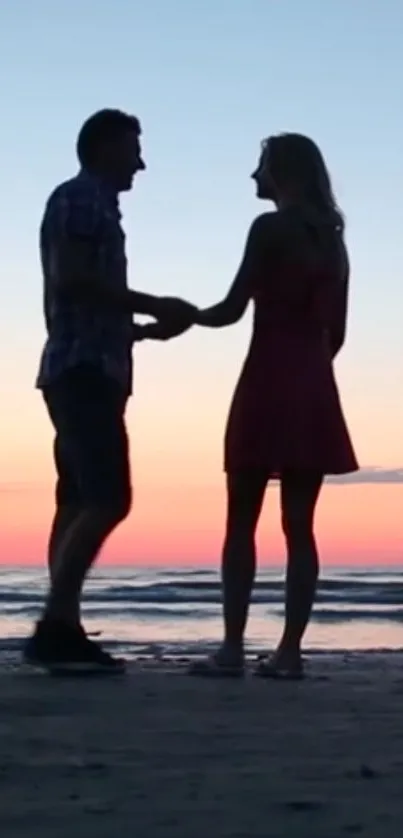 Silhouette of a couple at sunset on a beach, perfect mobile wallpaper.