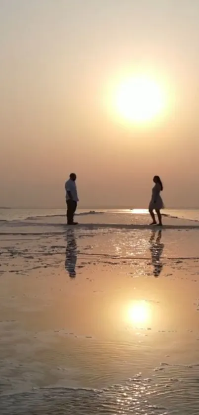 Silhouetted couple at sunset on beach with reflections.